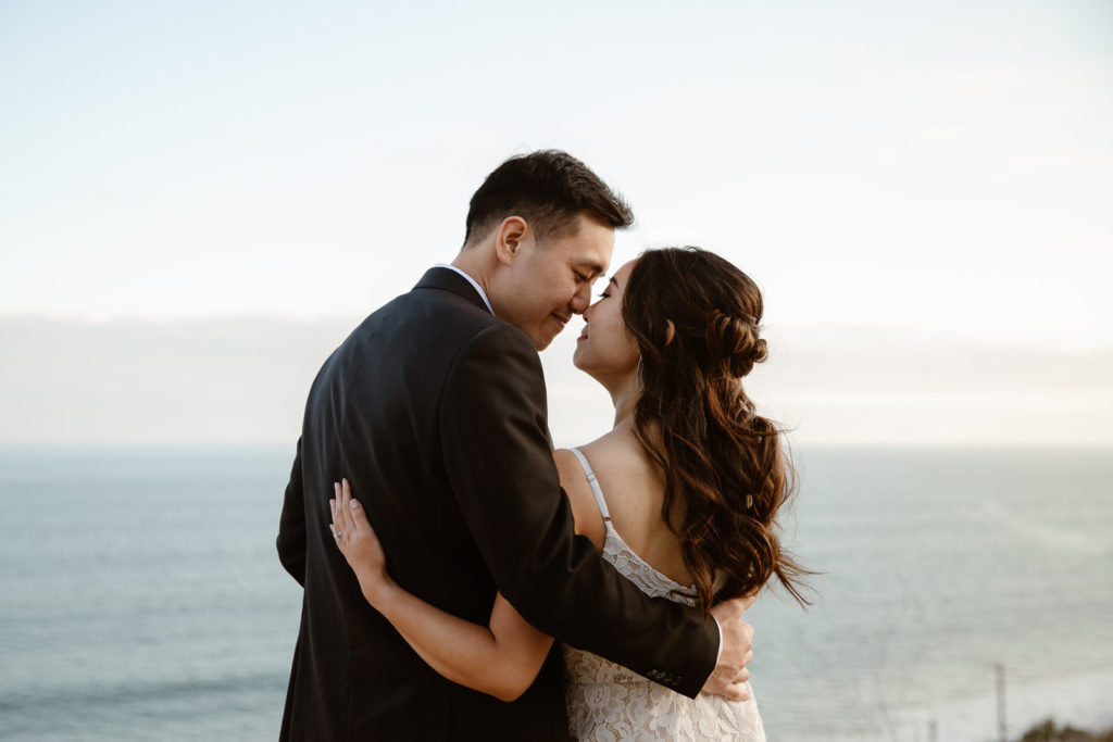 bride and groom embrace near the ocean